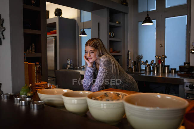 Vorderansicht einer jungen kaukasischen Frau, die in der Küche steht, ihren Laptop benutzt und lächelt. — Stockfoto