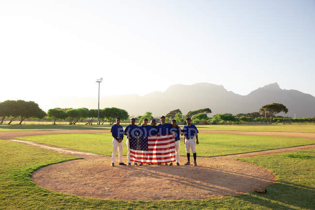 Бейсболисты стоят на линии с американским флагом — стоковое фото