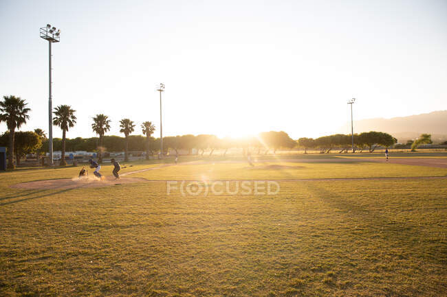 Великолепный вид на бейсбольное поле во время игры в солнечный день, с игроками на заднем плане — стоковое фото