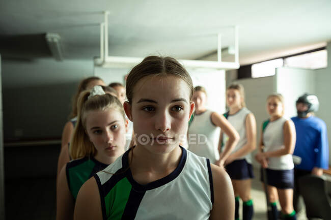 Портрет кавказьких хокеїсток, підготовка до гри, стояння в мінливій кімнаті, з її товаришами по команді стояти рядочком за нею. — стокове фото