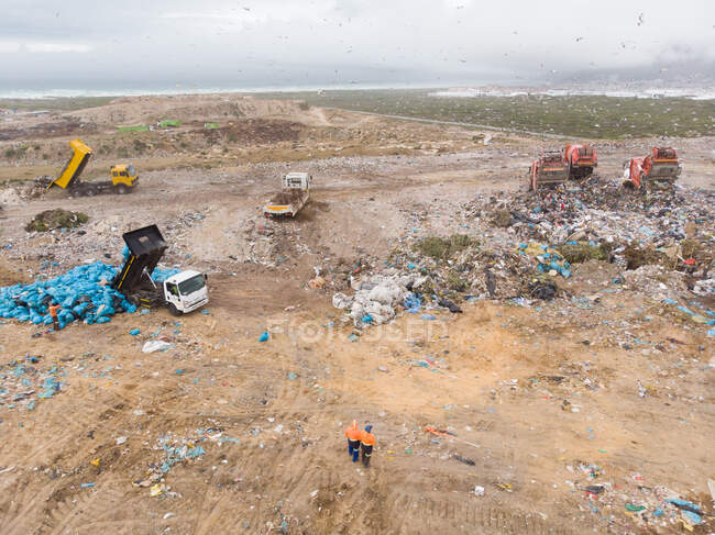 Drone tiro de veículos que trabalham e limpar e entregar lixo empilhado em um aterro cheio de lixo. Questão ambiental global da eliminação de resíduos . — Fotografia de Stock