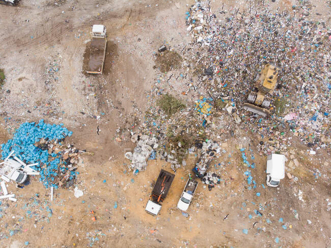 Drone shot de véhicules travaillant, déblayant et livrant des ordures empilées sur une décharge pleine de déchets. Enjeu environnemental mondial de l'élimination des déchets. — Photo de stock
