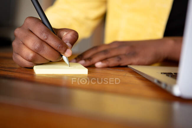 Front view mid section close up of woman sitting in her living room on a sunny day, writing in a notebook — Stock Photo