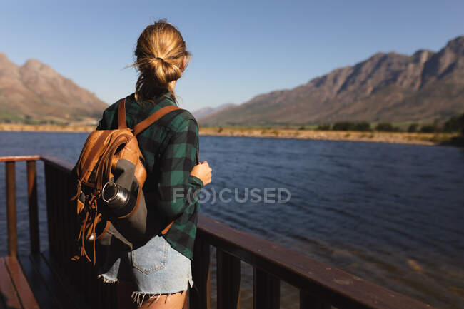 Vista posteriore di una donna caucasica che si diverte in un viaggio in montagna, in piedi su un balcone cabina, godendo la sua vista, in una giornata di sole — Foto stock