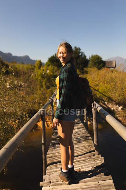 Rear view close up of a Caucasian woman having a good time on a trip to the mountains, standing on a bridge, looking at the camera, on a sunny day — Stock Photo
