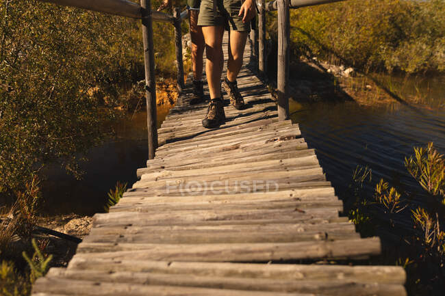 Vista frontal seção baixa do homem se divertindo em uma viagem às montanhas, andando em uma ponte, em um dia ensolarado — Fotografia de Stock