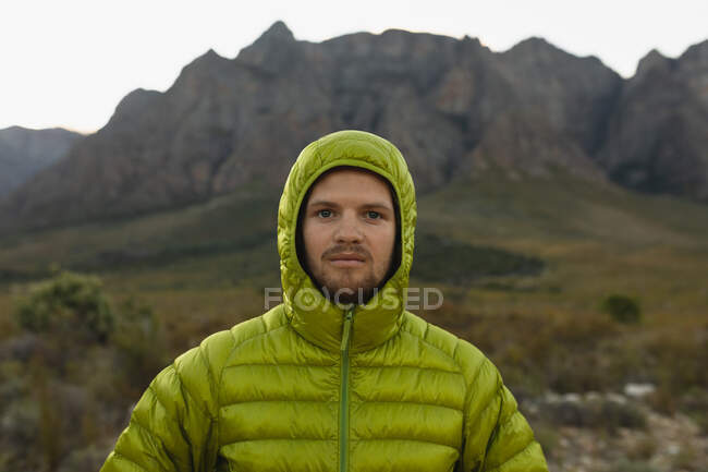 Porträt eines kaukasischen Mannes, der es sich auf einer Bergtour gut gehen lässt, warme Kleidung trägt und in die Kamera blickt — Stockfoto