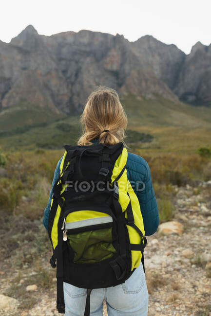 Visão traseira de uma mulher caucasiana se divertindo em uma viagem às montanhas, vestindo roupas quentes, apreciando sua vista — Fotografia de Stock