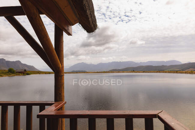 Дивовижний вид на гори з дерев'яної кабіни з балконом, з прекрасним озером між ними, в похмурий день — стокове фото