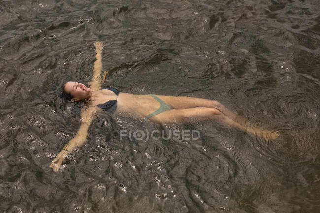 Hochwinkelaufnahme eines kaukasischen Paares, das eine gute Zeit auf einer Reise in die Berge hat, im See schwimmend, mit geschlossenen Augen — Stockfoto