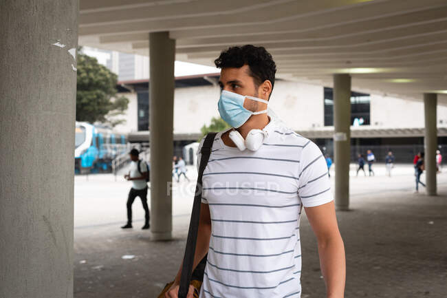 Vue de face d'un homme caucasien dans les rues de la ville pendant la journée, portant un masque facial contre la pollution atmosphérique et le coronavirus covid19. — Photo de stock