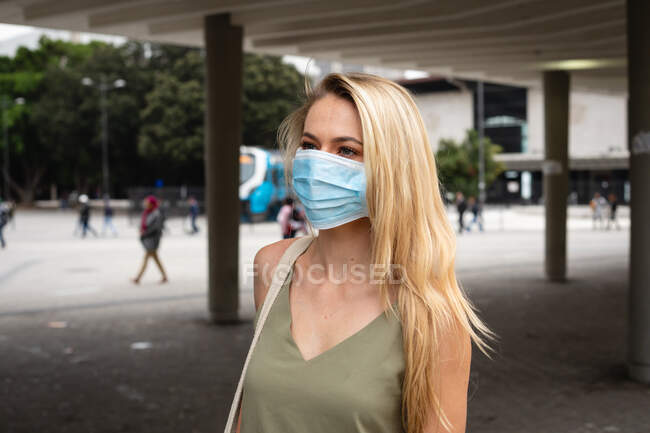 Vista frontal de uma mulher caucasiana nas ruas da cidade durante o dia, usando máscara facial contra a poluição do ar e covid19 coronavírus .. — Fotografia de Stock