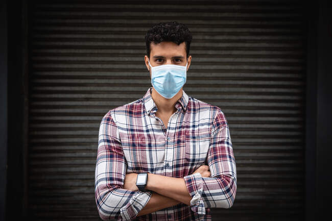 Retrato de um homem caucasiano com cabelo escuro curto, vestindo roupas casuais e máscara facial contra a poluição do ar e covid19 coronavírus, olhando diretamente para uma câmera . — Fotografia de Stock