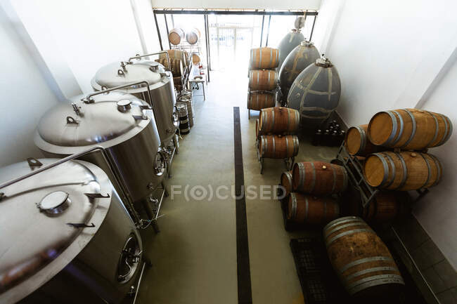 Vista ad alto angolo di un piccolo birrificio vano di fermentazione e stoccaggio con vasche e botti di legno poste lungo le pareti. — Foto stock