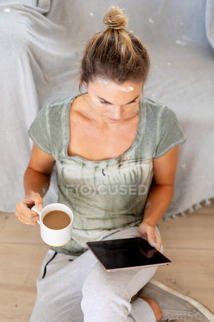 Frau in sozialer Distanz trinkt Kaffee und nutzt digitales Tablet — Stockfoto