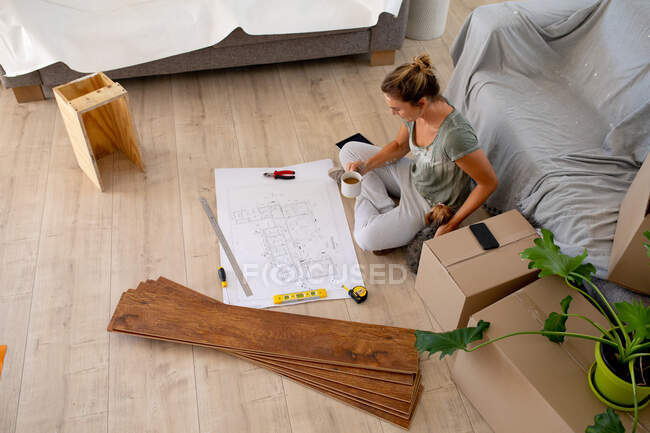 Mujeres en distanciamiento social sentadas en el suelo examinando un plan - foto de stock