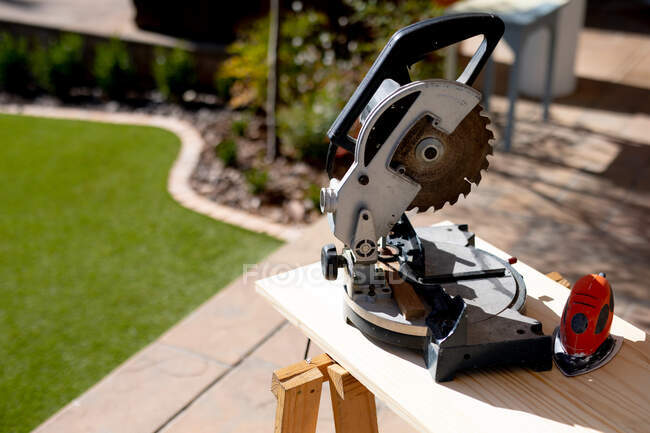 Großaufnahme einer Kreissäge, die an einem sonnigen Tag auf einer Werkbank im Garten steht — Stockfoto