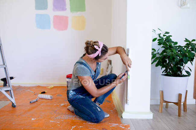 Caucasian woman spending time at home self isolating and social distancing in quarantine lockdown during coronavirus covid 19 epidemic, doing DIY, using a spirit level. — Stock Photo