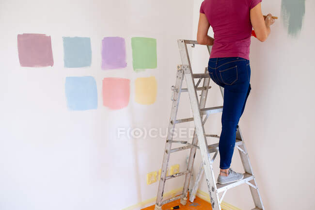 Low section of woman spending time at home self isolating and social distancing in quarantine lockdown during coronavirus covid 19 epidemic, painting the walls of her home. — Stock Photo