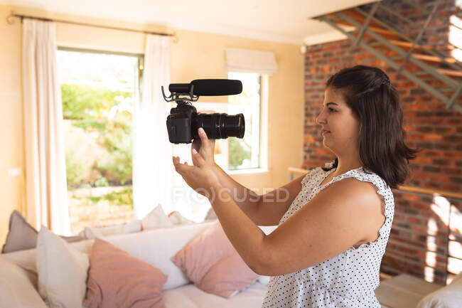 Кавказька жіночий блогер вдома, у своїй вітальні, використовуючи камеру, щоб підготувати свій онлайн-блог. Соціальна дистанція і самоізоляція в карантинному блокуванні.. — стокове фото