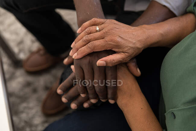 Африканська американська пара проводить час удома разом, спілкуючись та ізолюючи себе в карантині під час епідемії коронавірусу (19), сидячи на дивані та тримаючись за руки. — стокове фото
