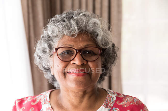 Portrait d'une femme afro-américaine âgée passant du temps à la maison, distanciation sociale et isolement personnel en quarantaine pendant l'épidémie de coronavirus covid 19, regardant la caméra et souriant — Photo de stock