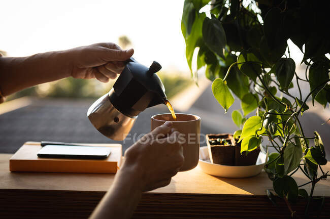 Mid section of woman spending time at home self isolating and social distancing in quarantine lockdown during coronavirus covid 19 epidemic, pouring coffee from a moka pot. — Stock Photo