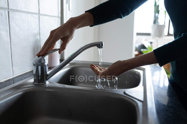 Sección media de la mujer lavándose las manos con jabón líquido. Distanciamiento social y autoaislamiento en cuarentena. - foto de stock
