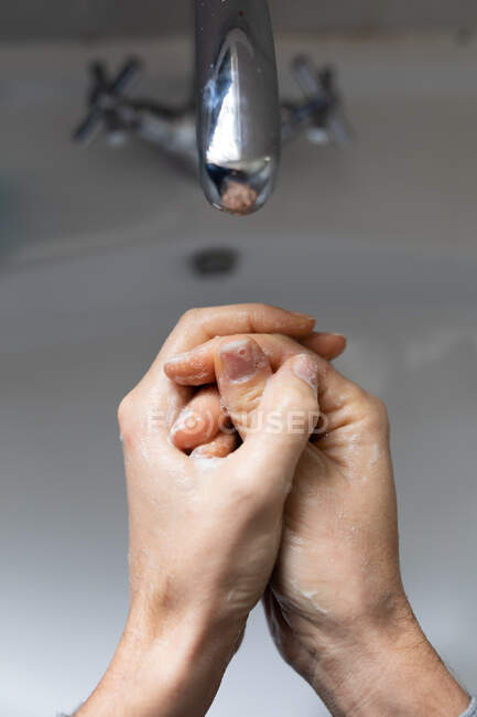 Feche no meio da seção da mulher usando camisola cinza, lavando as mãos com sabão líquido. Distanciamento social e auto-isolamento em quarentena . — Fotografia de Stock