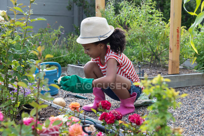 Afro-américaine fille social distanciation à la maison pendant quarantaine verrouillage, jardinage sur un jour ensoleillé. — Photo de stock