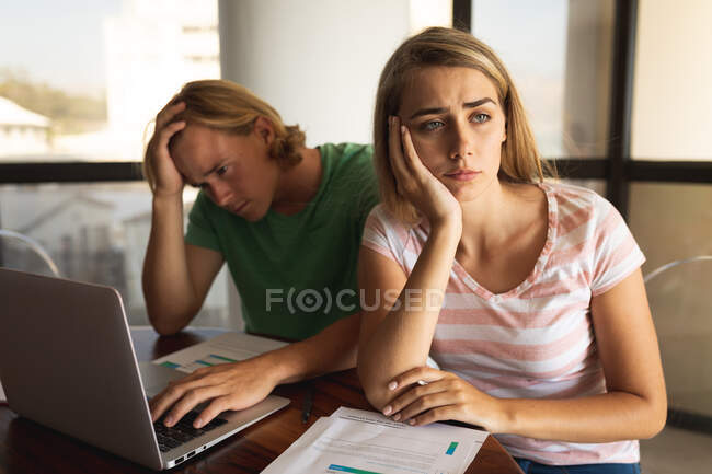 Caucasian couple sitting by a table, using a laptop, looking away from each other. Social distancing and self isolation in quarantine lockdown. — Stock Photo