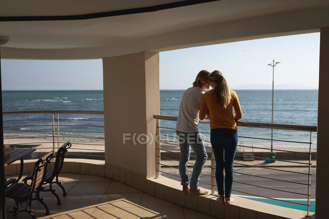 Kaukasisches Paar, das auf einem Balkon steht und sich umarmt. Soziale Distanzierung und Selbstisolierung in Quarantäne. — Stockfoto