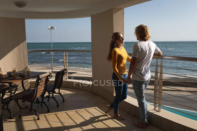 Kaukasisches Paar auf einem Balkon stehend, Händchen haltend. Soziale Distanzierung und Selbstisolierung in Quarantäne. — Stockfoto