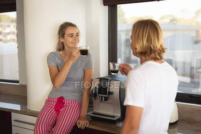 Kaukasisches Paar, das in der Küche steht, Kaffee trinkt und redet. Soziale Distanzierung und Selbstisolierung in Quarantäne. — Stockfoto