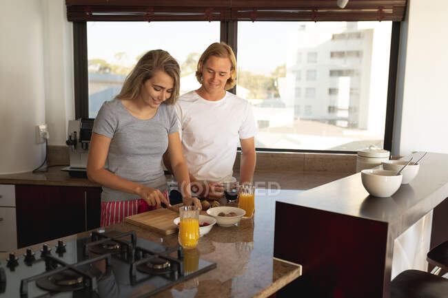 Kaukasisches Paar, das in einer Küche steht und gemeinsam frühstückt. Soziale Distanzierung und Selbstisolierung in Quarantäne. — Stockfoto