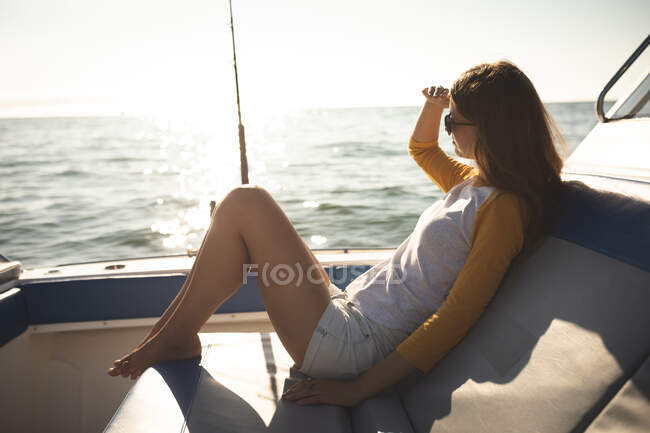 Ein jugendliches kaukasisches Mädchen genießt die Zeit in der Sonne an der Küste, sitzt auf einem Boot, entspannt, schaut weg — Stockfoto