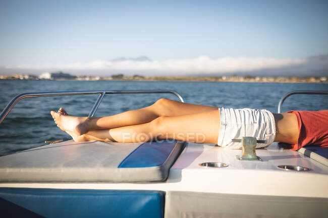 Parte média da menina desfrutando de seu tempo de férias ao sol pela costa, deitada em um barco, relaxante, olhando para longe — Fotografia de Stock