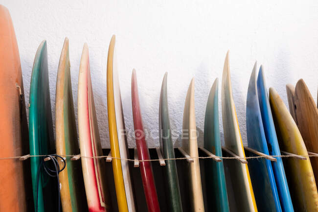 View of a set of colorful surfboards put in a rack by the wall in a surfboard makers studio — Stock Photo