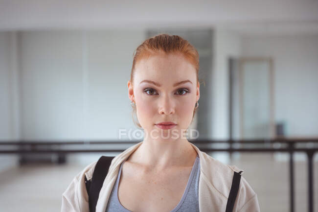 Caucasian attractive female ballet dancer with red hair wearing sportswear, entering a studio, preparing for a ballet class, looking into the camera. — Stock Photo