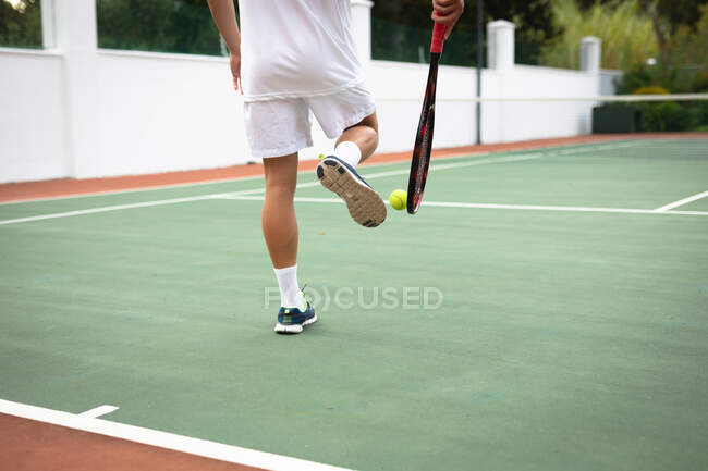 In der Mitte ein Mann in weißen Tennisanzügen, der an einem sonnigen Tag auf einem Platz Tennis spielt, einen Tennisschläger in der Hand hält und sich darauf vorbereitet, einen Ball zu treffen — Stockfoto