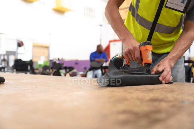 Male worker in a workshop at a factory making wheelchairs, standing at a workbench assembling parts of a product — Stock Photo