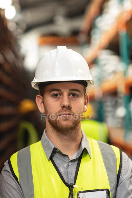 Portrait d'un ouvrier d'usine de sexe masculin caucasien portant un gilet haut vis regardant la caméra et portant un casque de sécurité. — Photo de stock
