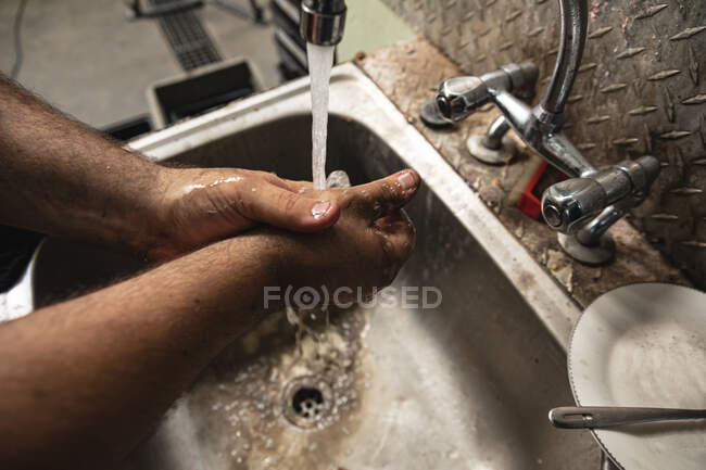 Close up de trabalhador da fábrica masculino em pé em uma pia e lavar as mãos sujas. — Fotografia de Stock