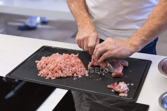 Средний вид секции, где мужчина-повар режет кусок рыбы острым ножом. Класс кулинарии на кухне ресторана. — стоковое фото