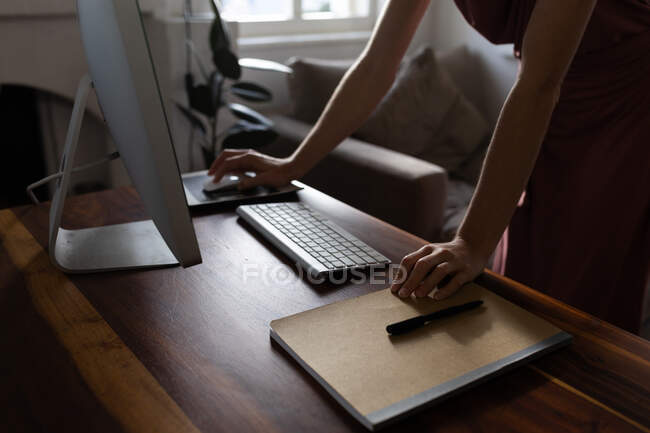 Середина жінки проводить час вдома, використовуючи свій комп'ютер, працюючи з дому. Спосіб життя в домашніх умовах ізоляція, соціальне дистанціювання в карантині під час пандемії коронавірусу 19 . — стокове фото