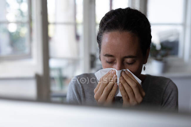 Una donna caucasica che passa del tempo a casa a soffiarsi il naso. Stile di vita a casa isolante, distanza sociale in isolamento di quarantena durante il coronavirus covid 19 pandemia. — Foto stock