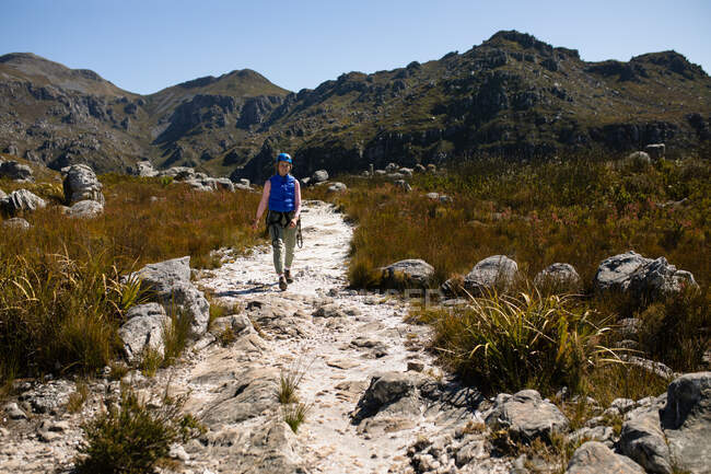 Vue de face de femme caucasienne profitant du temps dans la nature, portant un équipement de tyrolienne, randonnée par une journée ensoleillée dans les montagnes — Photo de stock