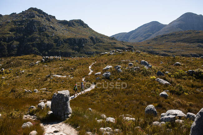 Vue latérale du couple caucasien profitant du temps dans la nature ensemble, portant un équipement de tyrolienne, randonnée par une journée ensoleillée dans les montagnes — Photo de stock