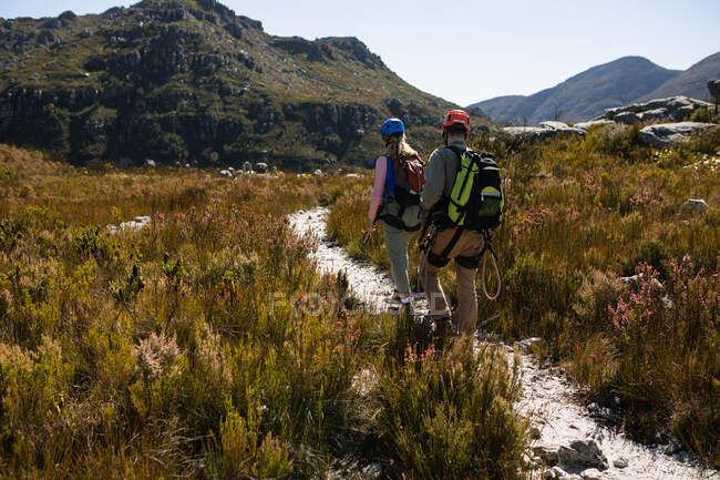 Vista posteriore della coppia caucasica godendo del tempo nella natura insieme, indossando attrezzature zip fodera, escursioni in una giornata di sole in montagna — Foto stock