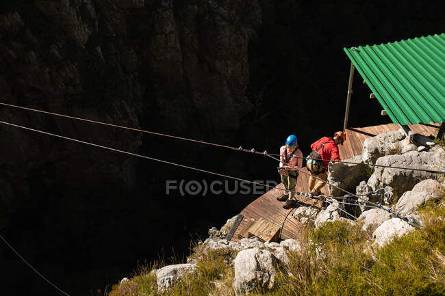 Vista ad alto angolo della coppia caucasica godendo del tempo nella natura insieme, preparandosi a zip line in una giornata di sole in montagna — Foto stock